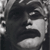 Pixelated grayscale image of a stylized face with dark hair, closed eyes, and a neutral expression, cropped to show only the upper portion of the head.