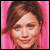 Pixelated close-up of a person with brown hair against pink background, static image.