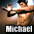 Pixelated image of a person in motion with outstretched arms, wearing dark hair and light clothing against a blurred background, with 'Michael' text at the bottom.