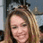 Two side-by-side pixelated images of a woman with long blonde hair, one showing her smiling and the other with lips parted as if speaking.