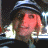 A 48x48 pixel buddy icon split into two frames showing a person with light hair wearing a dark cap and jacket on the left, next to green text reading "Original Icons .com" on a solid green background on the right.