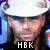 Pixelated image of a person wearing a white cap and dark clothing with text overlays including "HBK" and "I'M WITH STUPID GENAI!" on the left, and "I owns own you." on the right.