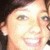Pixelated close-up of a smiling person with light skin, dark hair, and visible eyes and mouth against a dark background.