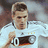 Pixelated image of a person in a white sports jersey with dark and red accents, holding an object near the chest.