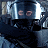 Pixelated static image showing a dark figure with light blue and white highlights against a dark background with two circular light patches.