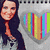 A pixelated image shows a person with long dark hair wearing a dark top and light pants, standing next to a large rainbow-colored heart shape on a gray background.