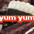 A close-up of a chocolate cake slice with white frosting, overlaid by red text reading 'yum yum' in two horizontal bands.