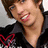 Pixelated image of a person with brown hair wearing dark clothing and red heart-shaped design, next to text on light purple background.