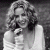 Black-and-white pixelated image of a woman with curly hair holding her hand near her face, next to green text reading 'Original Icons .com' on dark background.
