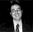 Black-and-white pixelated image of a person in a suit and tie, with two distinct facial expressions