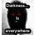 Pixelated black figure with red eyes, white mouth, and two text banners reading 'DARKNESS' above head and 'EVERYONE' below body on gray background.
