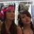 Two people with long dark hair stand side-by-side; one wears a pink headband with a bow, the other has a dark headpiece.