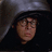 A 48x48 pixel animated buddy icon featuring a hooded figure with glasses in two frames: left frame shows the figure without text, right frame displays bold white text "I Can't Breathe In Here!!!" over the same character.