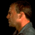 Pixelated static image of a person's profile with brown hair and light skin tone against black background, wearing gray clothing.