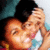 Two people in close physical proximity with one person's hand near the other's face, rendered in pixelated style with warm skin tones and dark hair.
