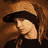 six pixelated images showing a person with long brown hair wearing a brown hat, striped shirt, and dark jacket, with a mouth with red lipstick and a lip piercing