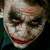 Pixelated close-up of a person with white face paint, dark eye makeup, and red lips forming a wide grin.