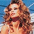 A pixelated close-up of a person with curly light brown hair against a blue background with white horizontal lines.