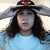 A person with long dark hair wears a light blue shirt and a wide-brimmed hat with red accents, shown in three