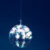 A spherical disco ball suspended by a thin cord against a solid dark blue background, reflecting light in a pixelated pattern.