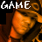Pixelated static image featuring a stylized orange-brown figure with the word "GAME" in white pixelated text above it against a black background.