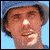 A person in a yellow shirt and helmet performs skateboard tricks against a blue sky, with one static portrait view.