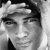 Black-and-white pixelated static image of a person's face with visible hair and facial features, rendered in grayscale tones on a transparent background.