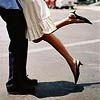 Static close-up of two people dancing on a street, focusing on lower bodies and legs in motion.