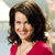 A static pixelated image of a person with shoulder-length dark brown hair wearing a red top against a blurred background.