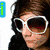 A static image of a person with brown hair wearing white sunglasses and dark clothing, partially overlaid by text elements.
