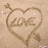 A heart-shaped drawing in sand with 'LOVE' written inside, an arrow piercing the top left of the heart, and a small curved line at the bottom right.