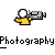 Pixelated character in yellow shirt holding camera with visible film strip, gray background, and text below.
