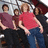 Group of people in casual clothing standing together with one person in red shirt and blue pants prominent.