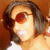 A person with shoulder-length dark hair wearing red-tinted sunglasses and a white top, shown in a of four with one blank