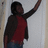 Pixelated figure in red shirt and dark jacket with arm raised against light background.