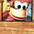 Pixelated character with brown fur, red shirt, and pink cap in repeated with yellow text overlays