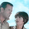 A four- shows two people against a light blue sky background, with text appearing in the top-right and bottom-left