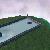 Pixelated landscape with a winding river, green terrain, and a small structure on a hill under a light purple sky.