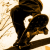 Pixelated figure in dark clothing with a white circular mark on the chest, set against a light background with scattered brown and beige pixels.