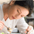 A pixelated image shows a person with light brown hair tied in a ponytail, wearing a white top, leaning forward with closed eyes and a slight smile.