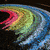 Animated sequence showing a rainbow arc transitioning from a dark background to a coastal landscape with water and hills.