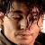 Pixelated close-up of a person's face with closed eyes, light skin tone, and dark hair, cropped tightly around the head.