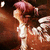 Animated icon of a character with pink hair in pigtails, wearing a white dress, turning head from left to right against a brown background.