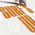 A pixelated orange and white checkered object with a dark top section, resembling a stylized vehicle or mechanical part, set against a light background.