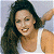 A pixelated image of a woman with long dark hair wearing a white tank top, smiling broadly while raising her right arm against a light gray background.