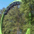 A pixelated landscape with a curved dark shape against green foliage and blue sky, showing no visible text or distinct subjects.