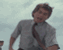 A man in a light gray shirt and dark tie performs a sequence of animated movements against a cloudy sky background.