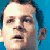 Pixelated close-up of a person's face with light skin, dark hair, and a blue background, showing eyes, nose, mouth, and ear details.