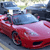 Pixelated image of a red sports car with a blue roof, positioned on a road with blurred background elements.