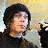 A person wearing a black beanie and dark shirt with a large golden pentagram symbol on the chest, shown in two side-by-side views against different backgrounds.